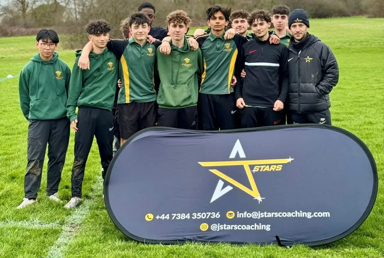 A J-Stars squad with their coaches beside the club banner